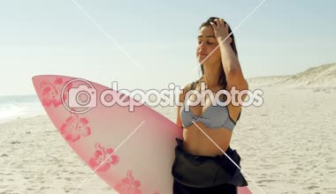 Kadın sörfçü saçları ile sahilde güneşli bir günde 4 k oynuyor. 