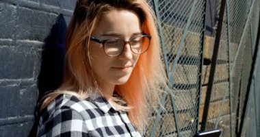 Güzel kadın cep telefonuyla duvara güneşli günde 4 k