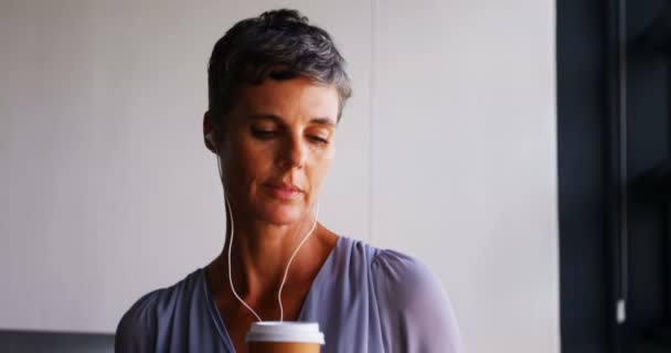 Mujer Negocios Tomando Café Mientras Escucha Música Teléfono Móvil Oficina — Vídeo de stock