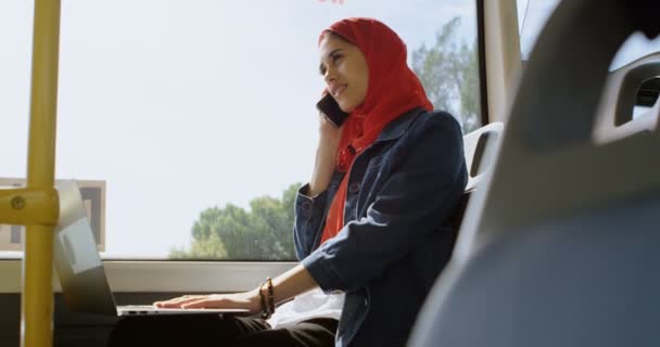 Nő a hidzsáb beszélő-ra mozgatható telefon rövid idő használ a laptop a buszon, 4k