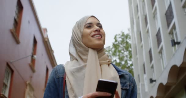 Szczęśliwa Kobieta Hidżab Przy Użyciu Telefonu Komórkowego Podczas Spaceru Ulicy — Wideo stockowe