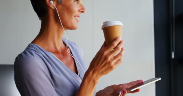 コーヒーを飲んでいる実業家オフィス で携帯電話で音楽を聞いている間 — ストック動画