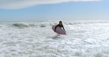 Kadın 4 k plajda denizin üzerinde çalışan surfboard ile