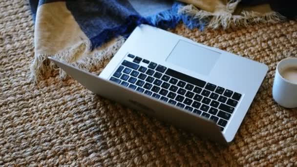 自宅のリビング ルームでマットの上のノート パソコンとコーヒーのマグカップ — ストック動画
