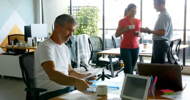 Uitvoerend Bezig Met Bureau Terwijl Zijn Collega Praten Achtergrond Kantoor — Stockvideo