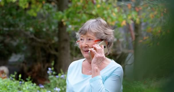 Homeyard で携帯電話で話している年配の女性 — ストック動画