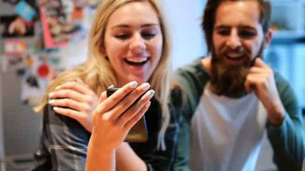 Романтическая Пара Улыбается Пользуясь Мобильным Телефоном Дома — стоковое видео