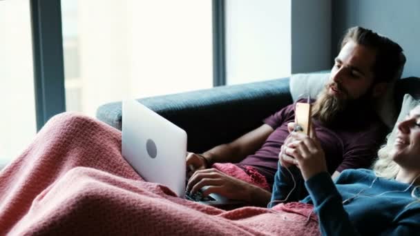 Pareja Escuchando Música Teléfono Móvil Mientras Usa Ordenador Portátil Sala — Vídeos de Stock