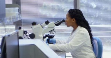 4 k laboratuarda mikroskop kullanarak bilim adamı yan görünüm