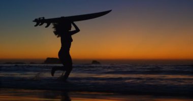 Kadın sörfçü surfboard ile n üzerinde plaj gece karanlığında 4 k yürüyüş