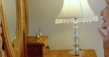 Gülümseyen kıdemli kadın yüzüne 4 k evde aynaya bakıyorum