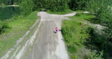 güneşli bir günde 4 k orman yolu üzerinde çalışan kadın jogger hava görünümünü 