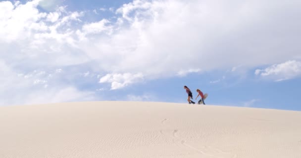 Couple avec planches de sable marchant sur la dune de sable par une journée ensoleillée 4k 