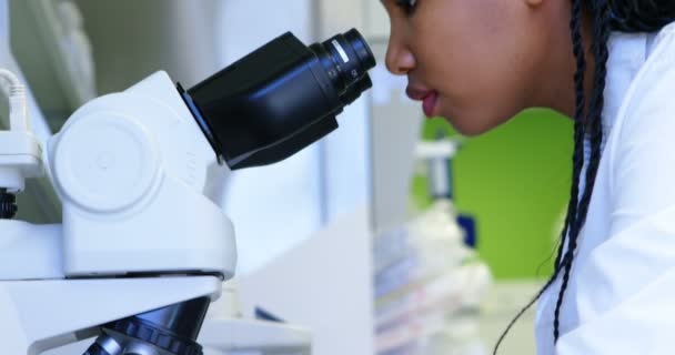 の研究室で顕微鏡を通して見る科学者 — ストック動画