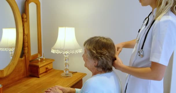 医生在家里的梳妆台上梳理老年妇女的头发4K — 图库视频影像