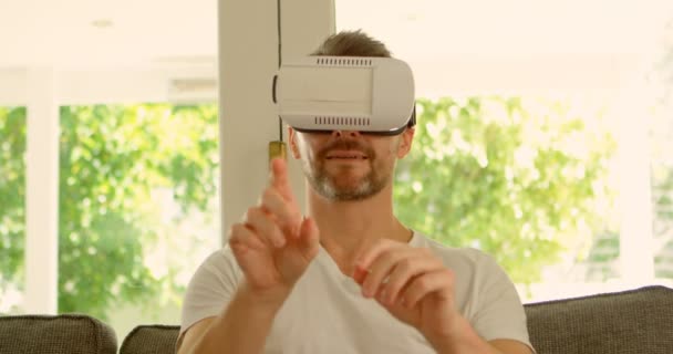 男子使用虚拟现实耳机在家沙发上4K — 图库视频影像