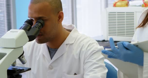 Wetenschapper Interactie Met Zijn Collega Tijdens Het Gebruik Van Microscoop — Stockvideo