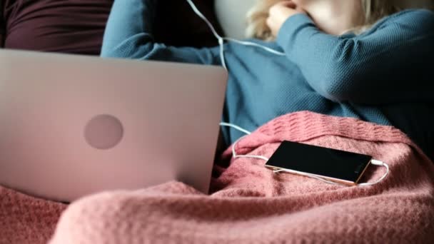 カップルのホーム でソファーでノート パソコンを使用しながら音楽を聴く — ストック動画