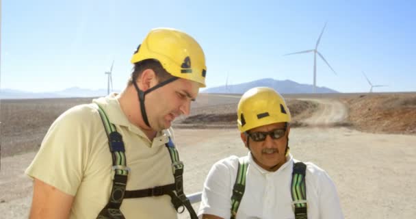 Два Инженера Обсуждают Ноутбуком Ветряной Электростанции Солнечный День — стоковое видео