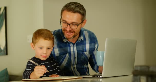 Πατέρας Κάνει Την Εργασία Στο Τραπέζι Στο Σπίτι Βλέποντας Γιο — Αρχείο Βίντεο