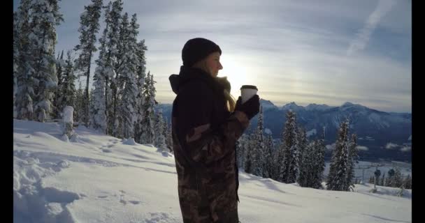 妇女与咖啡杯子站立在雪覆盖的风景在冬天4K — 图库视频影像