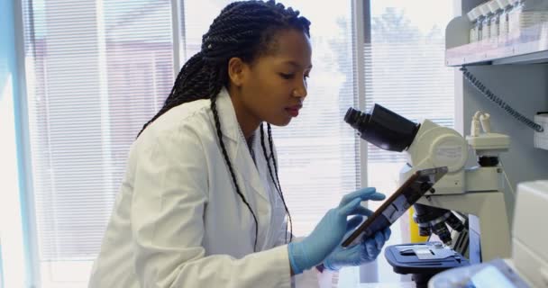 Wetenschapper Zoek Microscoop Tijdens Het Gebruik Van Digitale Tablet Laboratorium — Stockvideo