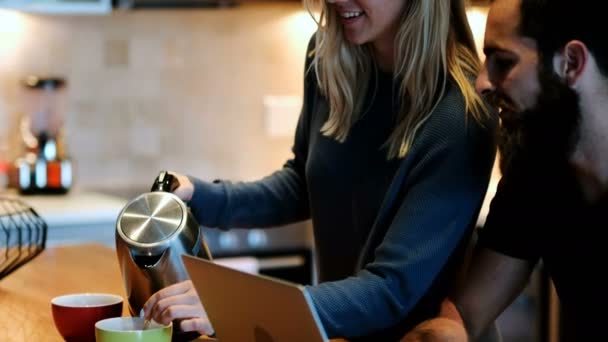 Mann Benutzt Laptop Während Frau Hause Kaffee Zubereitet — Stockvideo