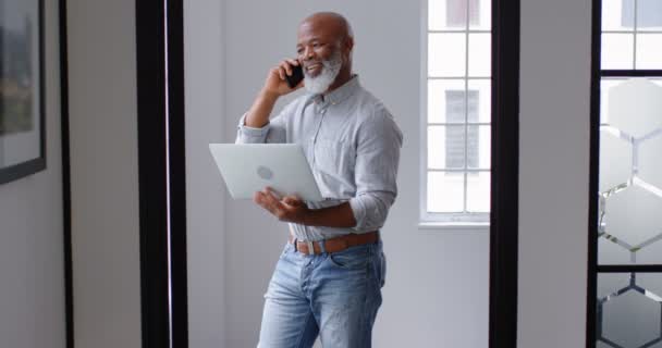 Бизнесмен Разговаривает Мобильному Телефону Время Использования Ноутбука Офисе — стоковое видео