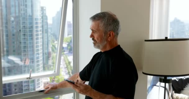 Hombre Tomando Teléfono Móvil Mientras Que Pie Cerca Ventana Casa — Vídeos de Stock