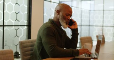 4 k ofiste dizüstü bilgisayar kullanırken cep telefonda konuşurken işadamı