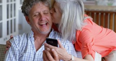 Mutlu üst düzey çift cep telefonuyla verandada 4 k