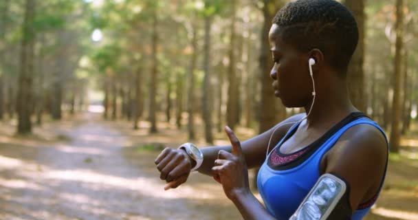 Femmina Jogger Utilizzando Smartwatch Nella Foresta Una Giornata Sole — Video Stock