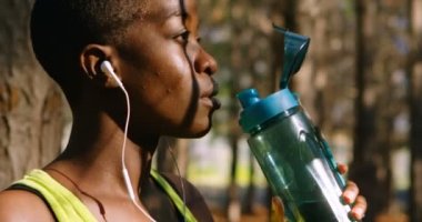 Kadın jogger İçmesuyu güneşli bir günde 4k ormanda