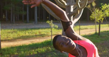 Genç kadın atlet orman 4 k müzik dinleme sırasında germe egzersiz gerçekleştirme