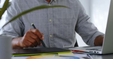 Orta Bölüm 4 k ofiste masa üzerinde grafik tablet kullanarak iş adamı