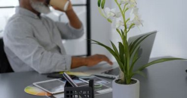 Office 4 k masada dizüstü bilgisayar kullanırken kahve olan işadamı