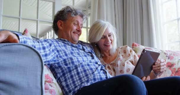 快乐的老年夫妇使用数码片在沙发上的家庭4K — 图库视频影像