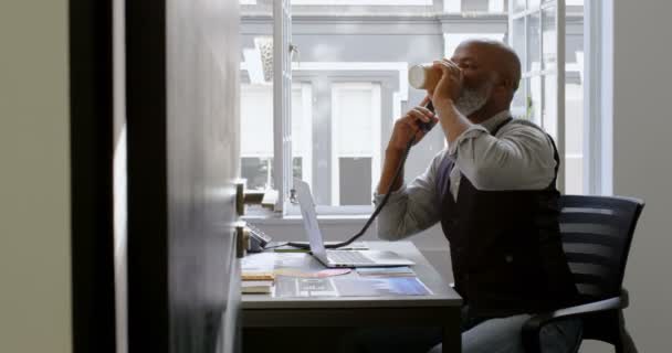 Empresario Tomando Café Mientras Habla Por Teléfono Fijo Usando Portátil — Vídeo de stock
