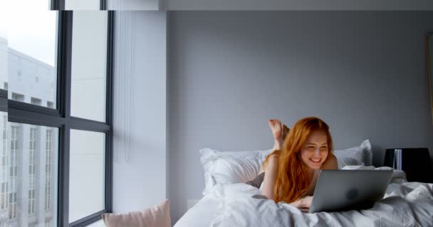 自宅の寝室でラップトップでビデオを作る美しい女性コール — ストック動画