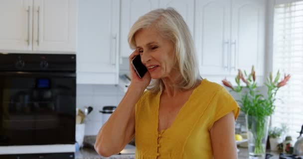 Mujer Mayor Hablando Por Teléfono Móvil Cocina Casa — Vídeos de Stock