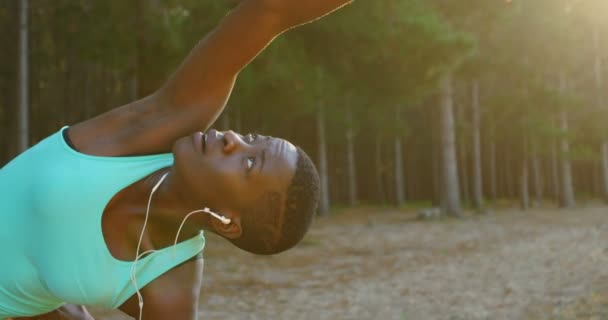 Young Female Athlete Performing Stretching Exercise While Listening Music Forest — Stock Video