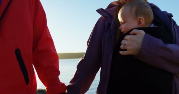 父母一起走在阳光明媚的日子里抱着孩子4K — 图库视频影像