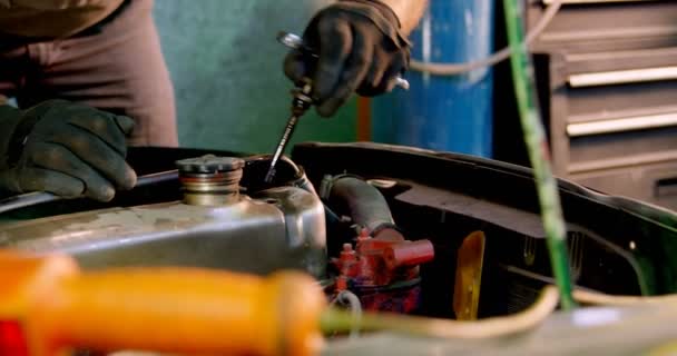 Mécanicien masculin entretenant une voiture dans le garage 4k 