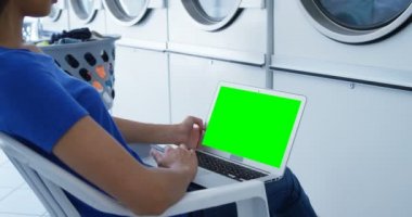 4 k çamaşırhanede dizüstü bilgisayar kullanan kadın orta bölümünde