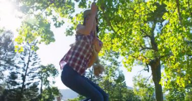Güneşli bir günde 4 k Park ip asılı ile oynayan kadın