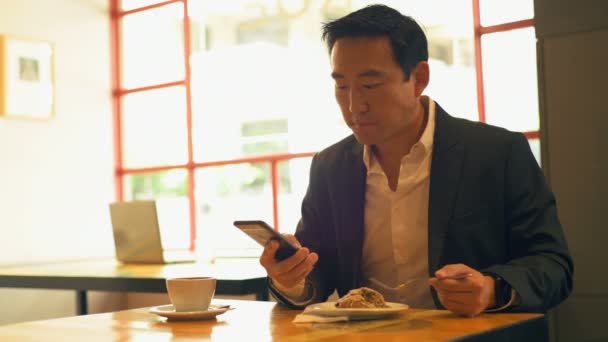 Empresario Que Tiene Comida Mientras Usa Teléfono Móvil Cafetería — Vídeos de Stock