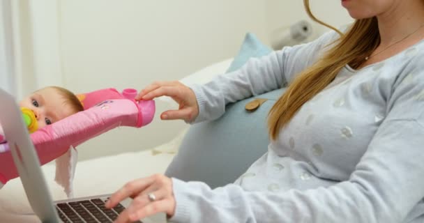 Mãe Olhando Para Bebê Enquanto Usa Laptop Casa — Vídeo de Stock