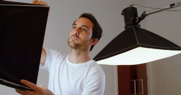 男摄影师调整闪光灯在摄影棚4K — 图库视频影像