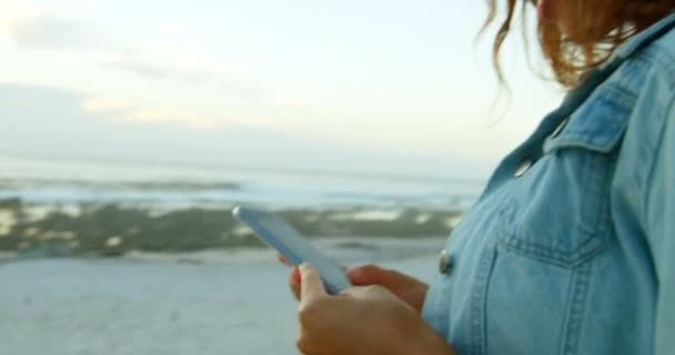 女性のビーチでの夕暮れ 携帯電話を使用して — ストック動画