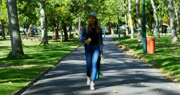 Hermosa Mujer Con Monopatín Caminando Por Calle Cerca Del Parque — Vídeo de stock